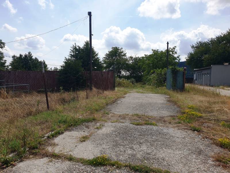 Der befestigte Weg führt durch Grundstücke - kommerziell in Trenčianske Bohuslavice, umgeben von Grün.