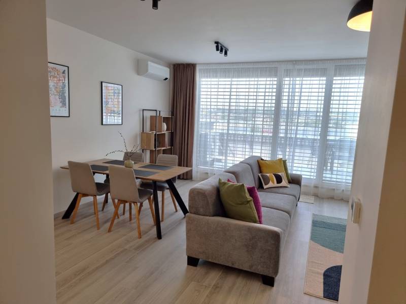 Das Wohnzimmer in der 3-Zimmer-Wohnung enthält ein Sofa, einen Esstisch und ein großes Fenster.