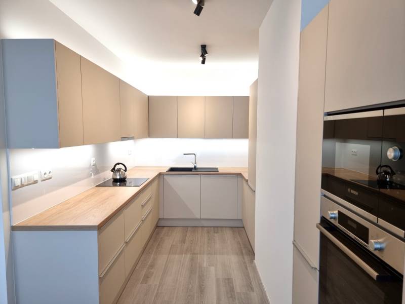 Küche mit einer Arbeitsplatte aus Holz und eingebauten Geräten in einer 3-Zimmer-Wohnung.