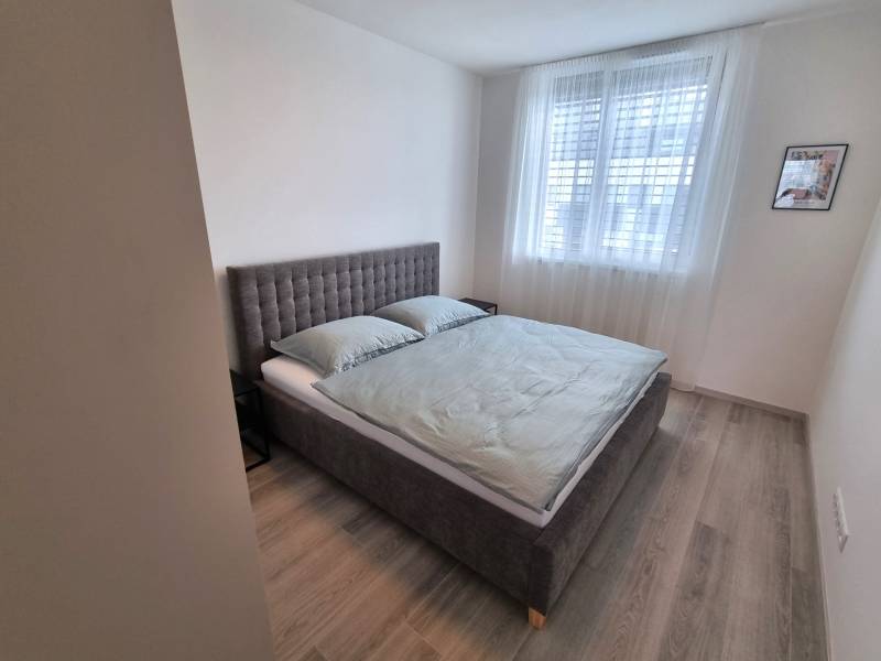 Schlafzimmer mit grauem Bett und hellen Möbeln in einer 3-Zimmer-Wohnung.