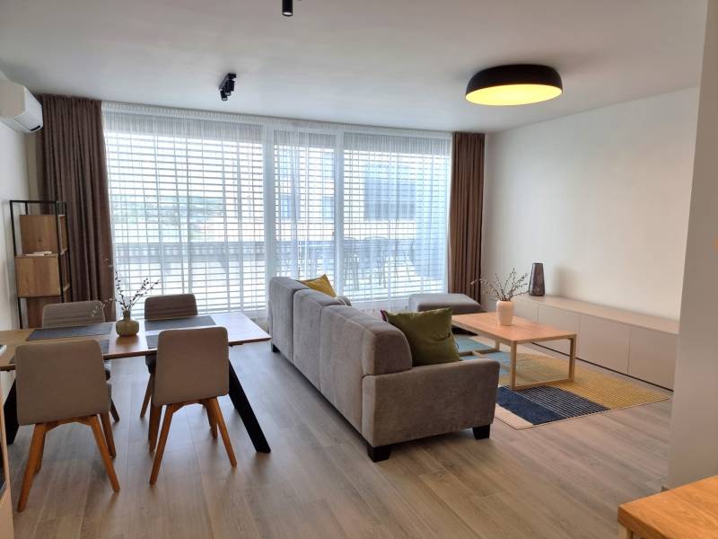 Wohnzimmer einer 3-Zimmer-Wohnung mit Esstisch, Sofa und großen Fenstern.