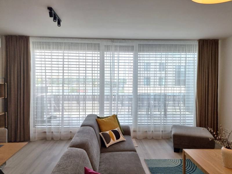 Wohnzimmer in einer 3-Zimmer-Wohnung mit einem bequemen Sofa und großen Fenstern.