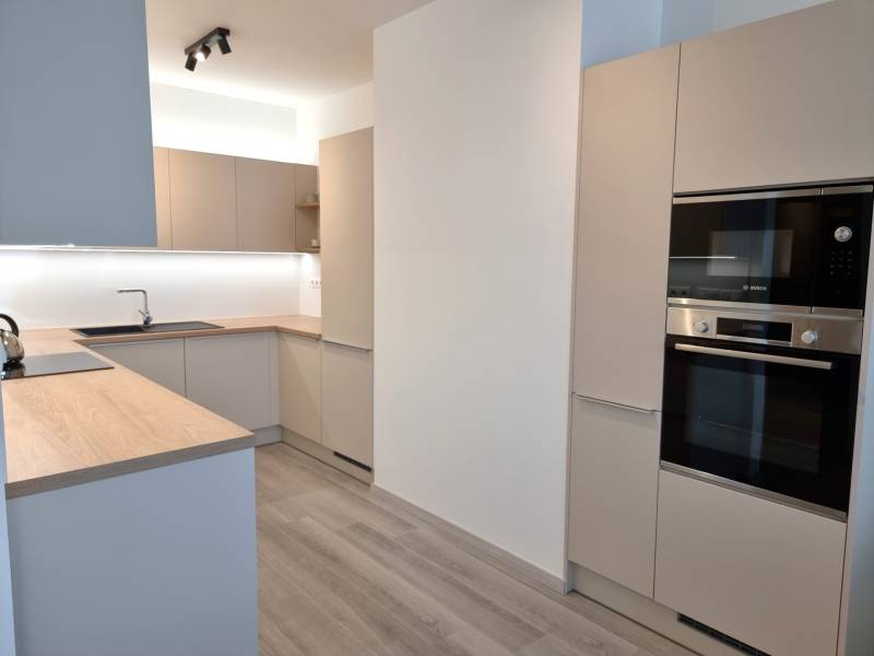 Moderne Küche in einer 3-Zimmer-Wohnung mit Holzarbeitsplatte und eingebauten Geräten.