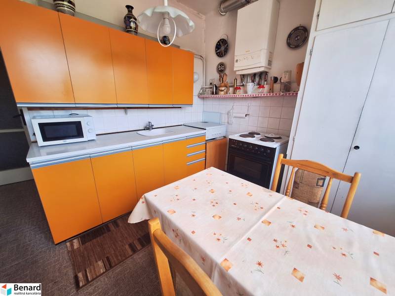 Küche einer 2-Zimmer-Wohnung mit gelben Schränken und Esstisch.