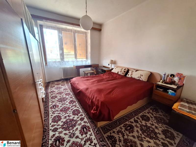 Schlafzimmer in einer 2-Zimmer-Wohnung mit Doppelbett, Teppich, Schränken, Fenster mit Heizkörper.