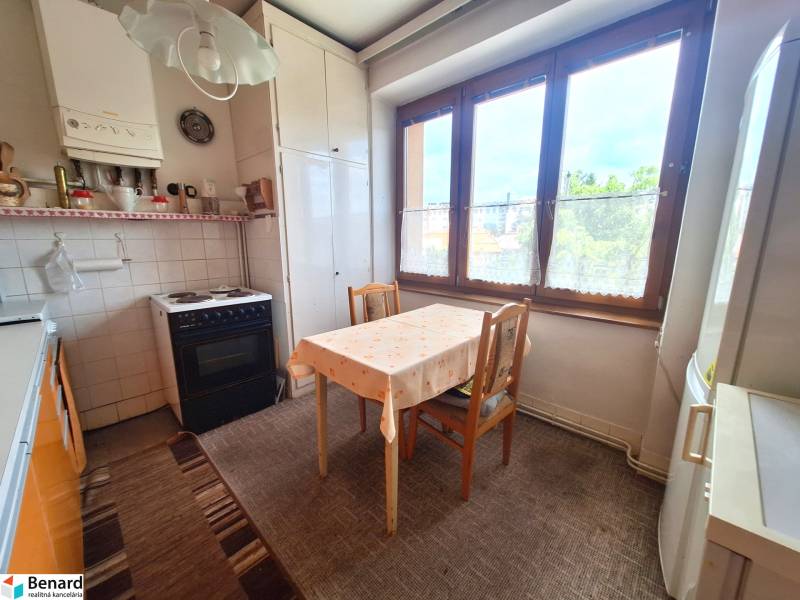 Küche in einer 2-Zimmer-Wohnung mit Tisch, Stühlen, Herd und großem Fenster.