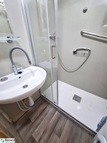 Badezimmer in einer 2-Zimmer-Wohnung mit Waschbecken, Duschkabine und Laminatboden.