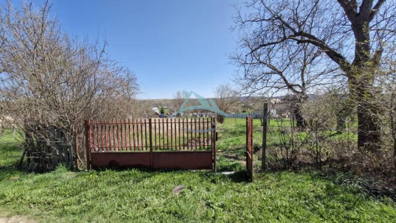 Freie Baugrundstücke mit Tor, umgeben von Frühlingsnatur und mit Blick auf die Landschaft.