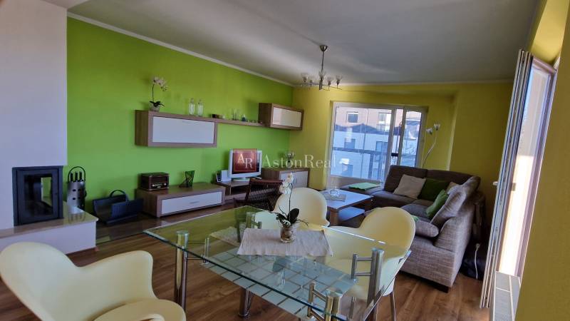 Wohnzimmer mit Kamin in einer Ferienwohnung, grüne Wände, bequeme Sitzgelegenheiten.
