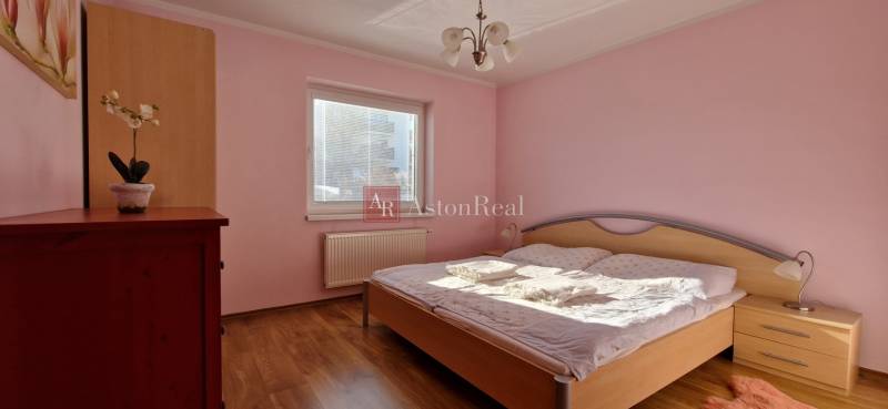 Schlafzimmer in einer Ferienwohnung mit Holzboden, rosa Wänden und einem Bett.