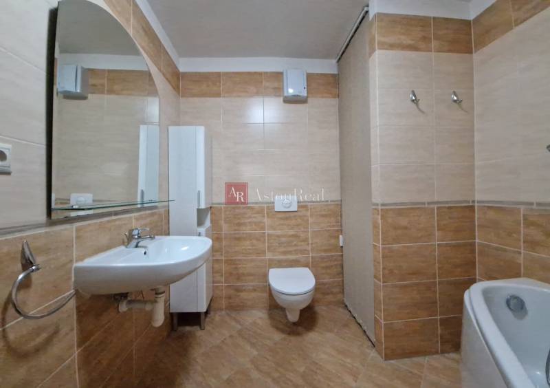 Badezimmer in einer Ferienwohnung mit Waschbecken, Spiegel und Toilette, gefliest mit braunen Fliesen.