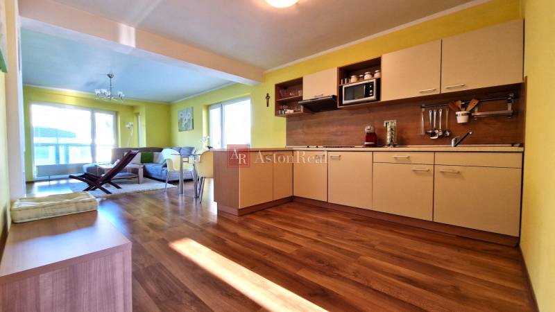 Helle Küche mit Sofa im Ferienapartment, offener Raum mit Holzboden.