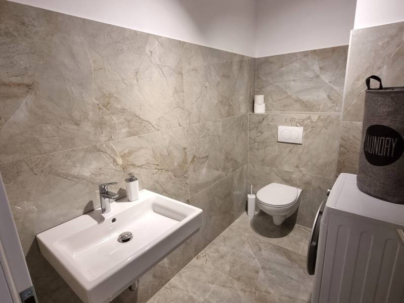 Badezimmer in einer 3-Zimmer-Wohnung mit Waschbecken, Toilette und Waschmaschine, gefliest.