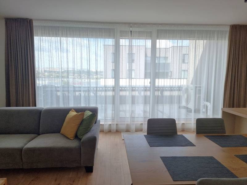 Wohnzimmer einer 3-Zimmer-Wohnung mit Sofa, Esstisch und Blick auf den Balkon.