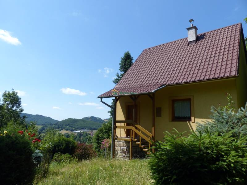 Eine Hütte in Štiavnické Bane, umgeben von Grün und mit Blick auf die Hügel im Hintergrund.