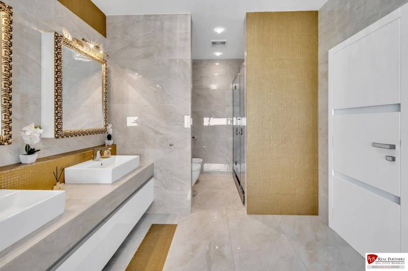 Luxuriöses Badezimmer mit Doppelwaschbecken und goldenen Details in einer 4-Zimmer-Wohnung.