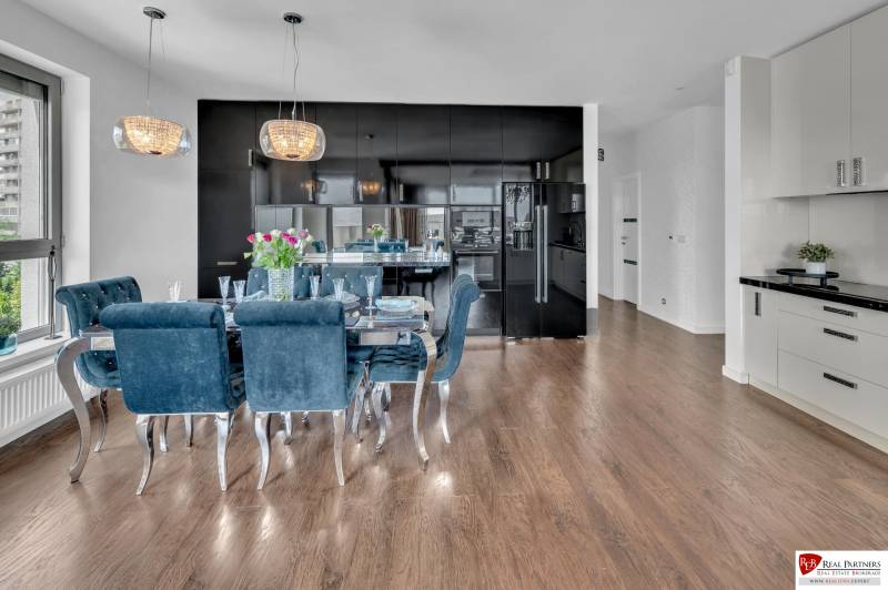 Küche in einer 4-Zimmer-Wohnung mit dunklen Schränken, Esstisch und Holzboden.