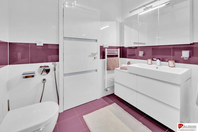 Badezimmer in einer 4-Zimmer-Wohnung mit violetten Fliesen und moderner Ausstattung.