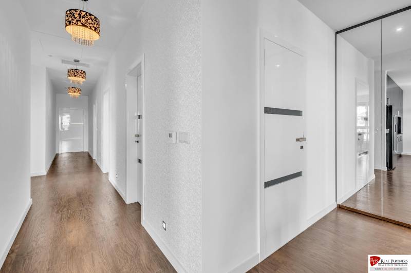 Flur einer 4-Zimmer-Wohnung mit einem Spiegelschrank und Holzboden.