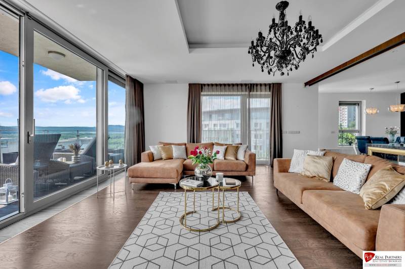 Ein stilvolles Wohnzimmer in einer 4-Zimmer-Wohnung mit einem Sofa, einem Kronleuchter und Blick auf die Terrasse.