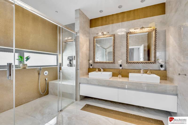 Luxuriöses Badezimmer mit zwei Waschbecken, Spiegeln und einer Duschkabine in einer 4-Zimmer-Wohnung.