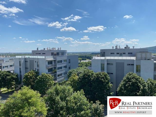 Ein Blick auf moderne Wohnblöcke in Bratislava - Karlova Ves, umgeben von Grün und blauem Himmel.