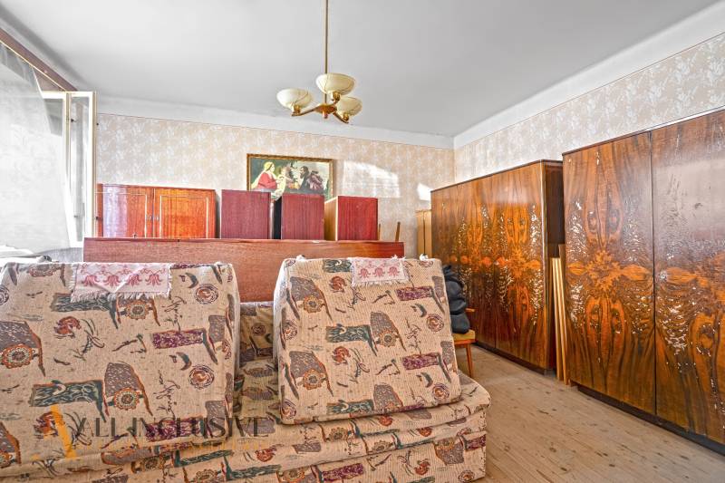 Ein Zimmer in einem Einfamilienhaus mit antiken Möbeln und dekorativen Tapeten.
