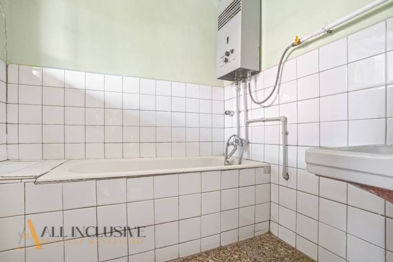 Ein Badezimmer in einem Einfamilienhaus mit weißen Fliesen und einem Gas-Wassererhitzer.