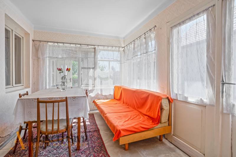 Innenraum eines Einfamilienhauses mit Sofa, Esstisch und Blumendekoration in einer Vase.
