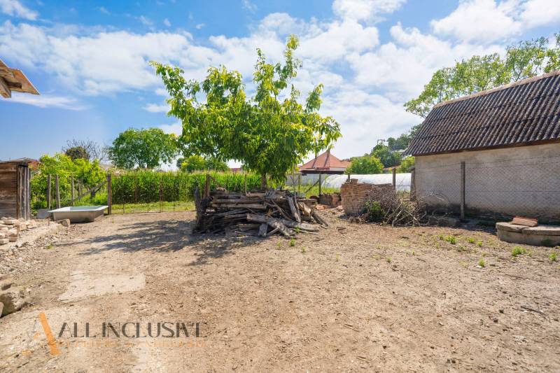 Ein Hof mit einem Holzstapel neben einem Einfamilienhaus in Jahodná, mit blauem Himmel.