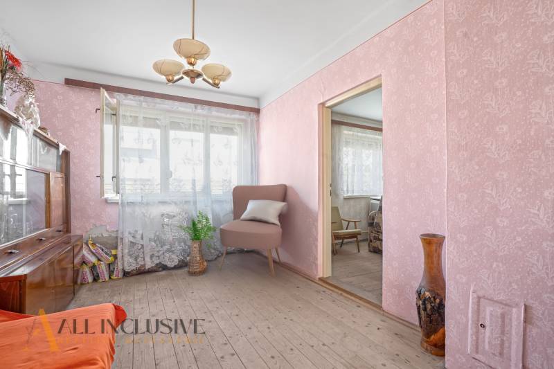 Ein Zimmer in einem Einfamilienhaus mit Tapeten, einem Sessel und Blumendekoration.