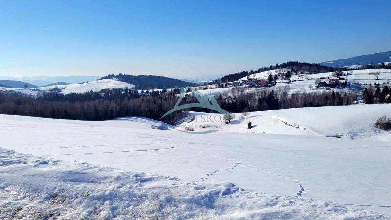 Verschneite Landschaft mit Hügeln und Wäldern, idealer Ort zum Wohnen. Grundstücke sind gut sichtbar.