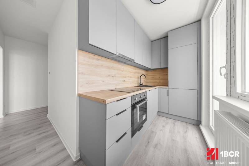 Helle Küche mit Holzarbeitsplatte in einer Zweizimmerwohnung.