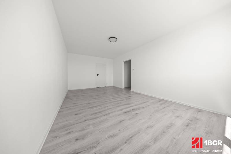 Geräumiges Zimmer mit Laminatboden und weißen Wänden in einer 2-Zimmer-Wohnung.