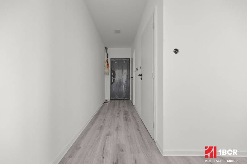 Flur in einer 2-Zimmer-Wohnung mit Laminatboden und weißen Wänden.