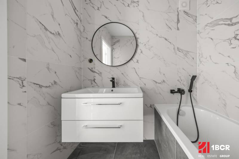 Badezimmer mit Marmorboden und Badewanne in einer 2-Zimmer-Wohnung.