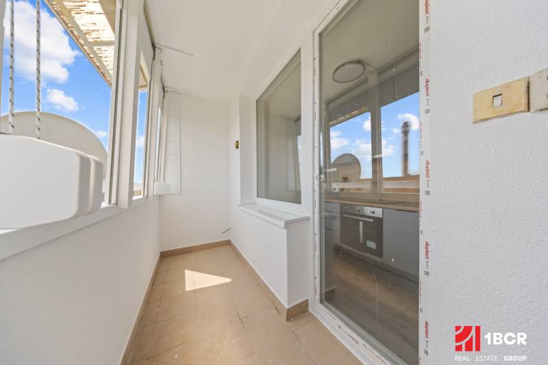 Helles Loggia in einer 2-Zimmer-Wohnung mit Zugang zur Küche und Blick nach draußen.