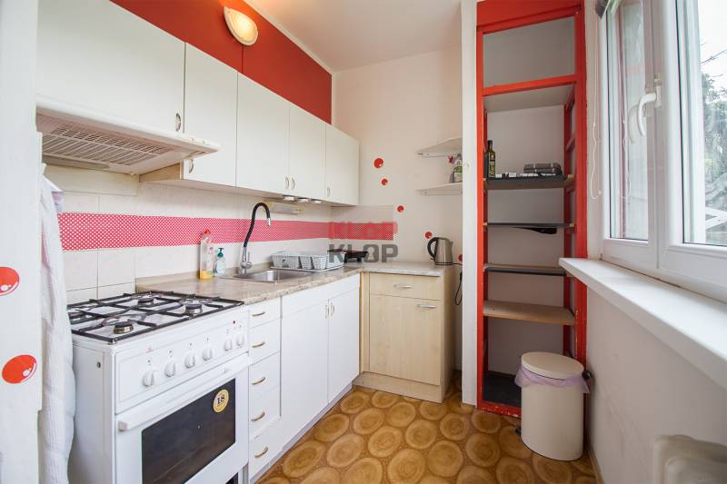 Küche in einer 2-Zimmer-Wohnung mit weißen Schränken und einem Gasherd.