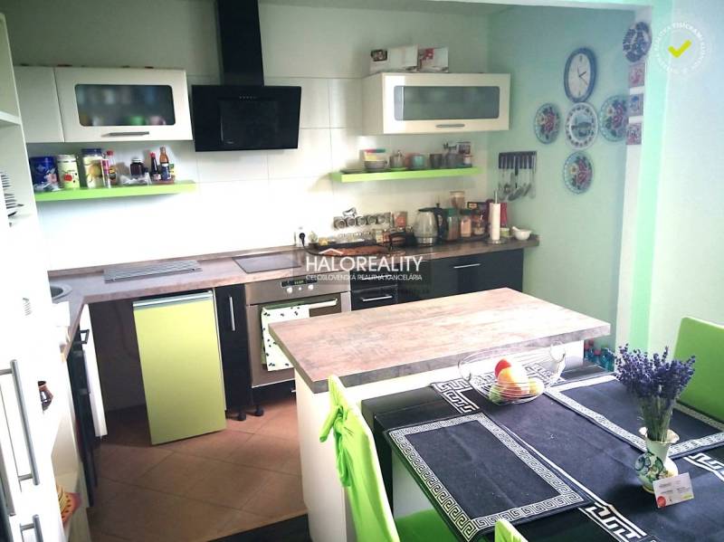 Eine Küche in einem Einfamilienhaus mit grünen und weißen Schränken und einem Esstisch.