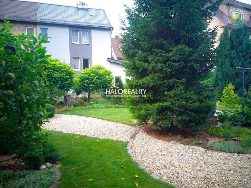 Ein schöner Garten mit einem Weg bei einem Einfamilienhaus in Nováky, umgeben von Grün und Bäumen.