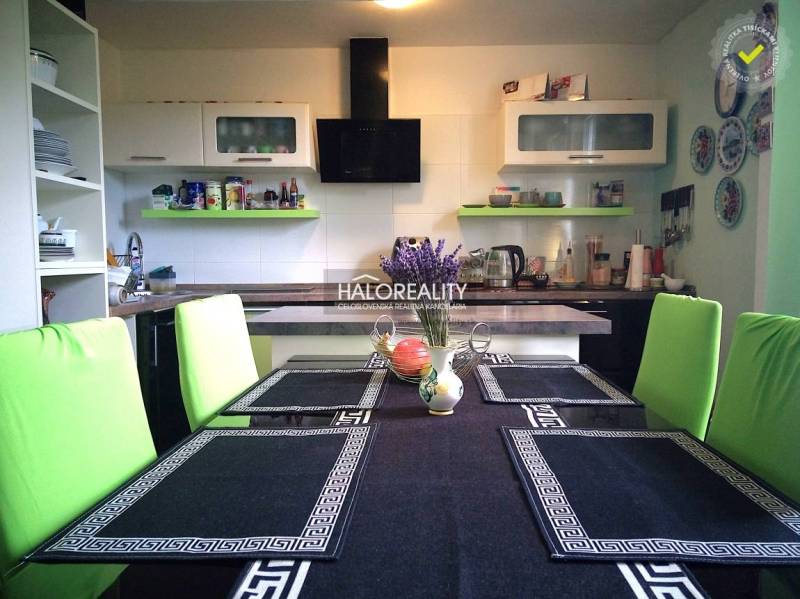 Küche in einem Einfamilienhaus mit Esstisch, grünen Stühlen und Küchenausstattung.