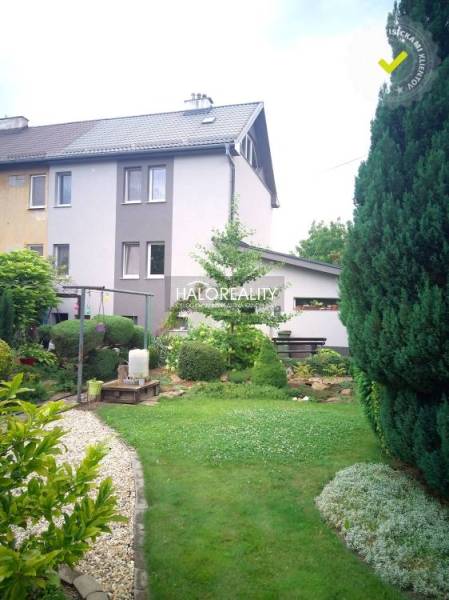 Ein Garten bei einem Einfamilienhaus in Nováky mit Bäumen und einem Kiesweg.