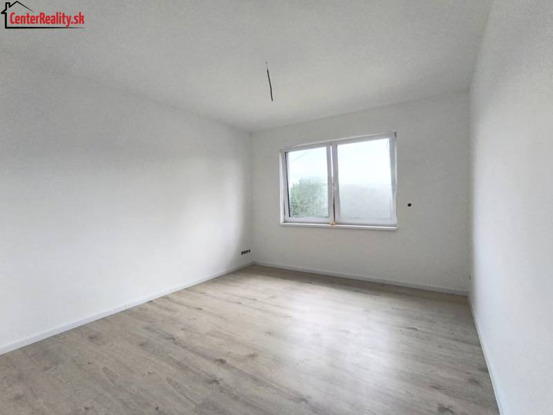 Innenraum eines Zimmers in einem Einfamilienhaus mit weißen Wänden und hellem Holzboden.
