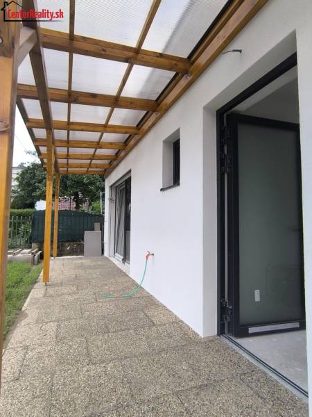 Die Terrasse des Einfamilienhauses in Malé Kršteňany mit einem Dachüberstand und Zugang zum Garten.