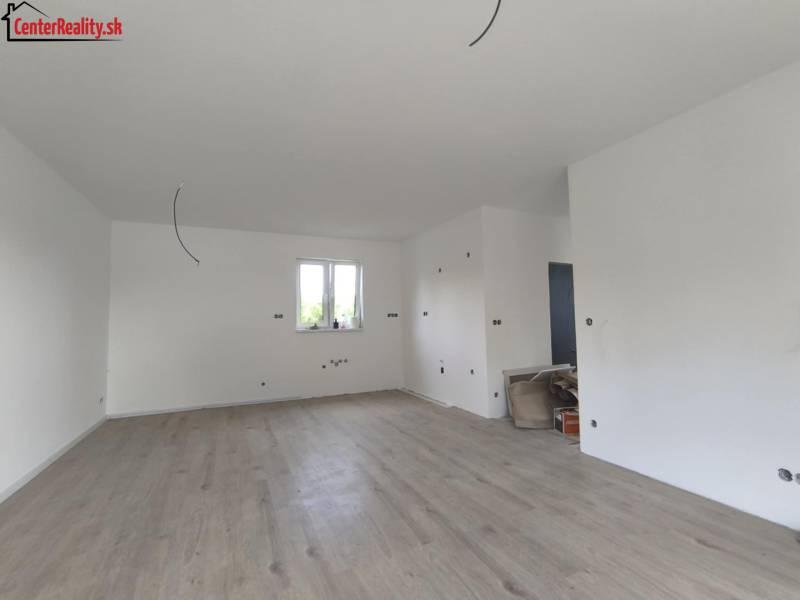 Innenraum eines Einfamilienhauses mit Holzboden, weißen Wänden und Vorbereitung für Elektroinstallation.