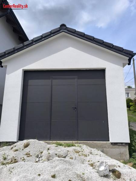 Ein Einfamilienhaus in Malé Krštenany mit einer weißen Garage und dunklen Türen.