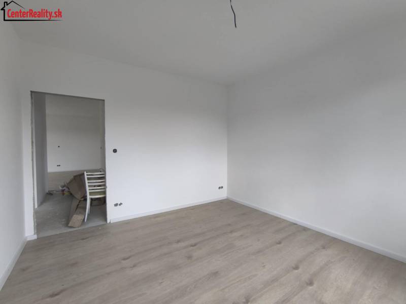 Ein leerer Raum mit weißen Wänden und hellem Holzboden in einem Einfamilienhaus.