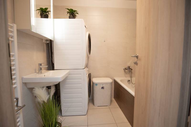 Badezimmer in einer 3-Zimmer-Wohnung mit Waschmaschine, Trockner und Badewanne.