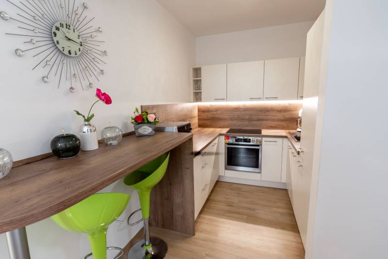 Küche mit Bartisch, grünen Stühlen und Dekorationen in einer 3-Zimmer-Wohnung.