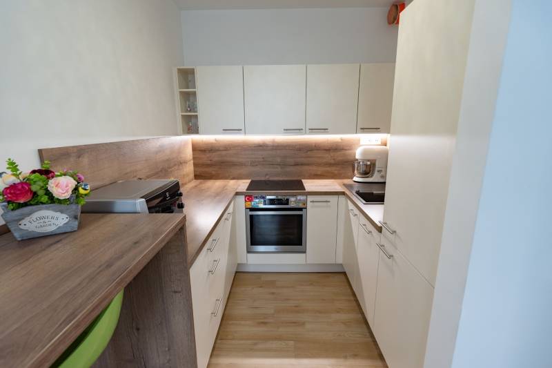 Küche in einer 3-Zimmer-Wohnung mit hellen Möbeln und einer Arbeitsplatte aus Holz.
